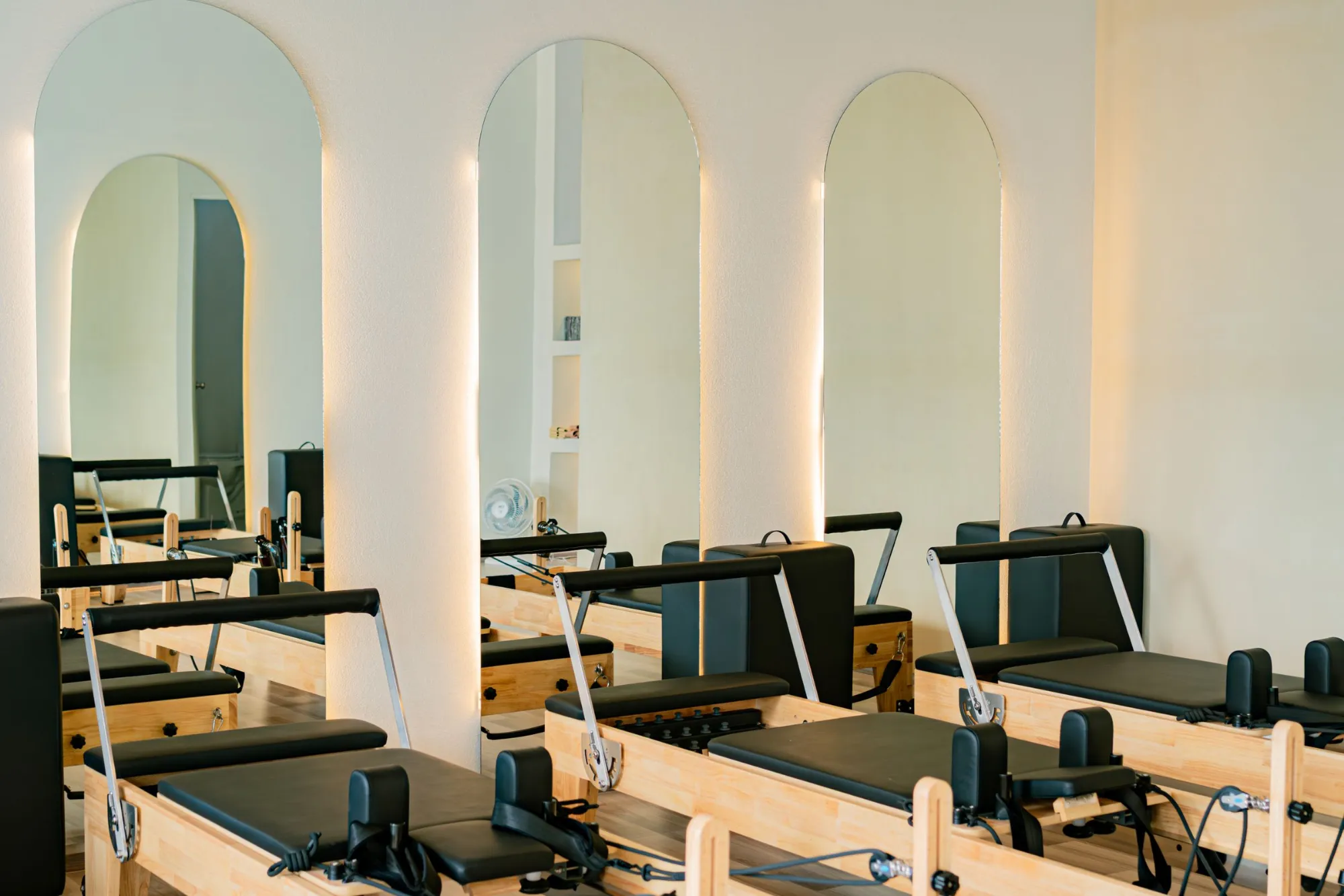 Kemerli, aydınlık bir pilates stüdyosunda sıralanmış reformer aletleri