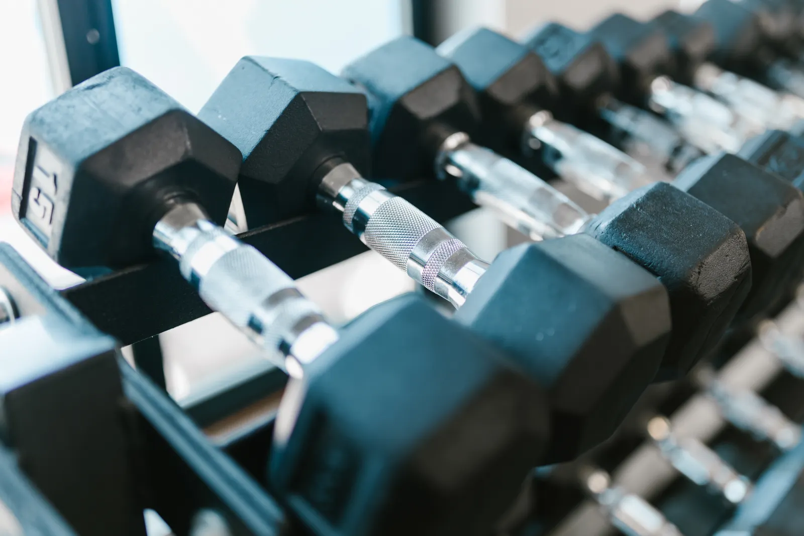 Aydınlık bir spor salonunda rafta dizili dambıllar