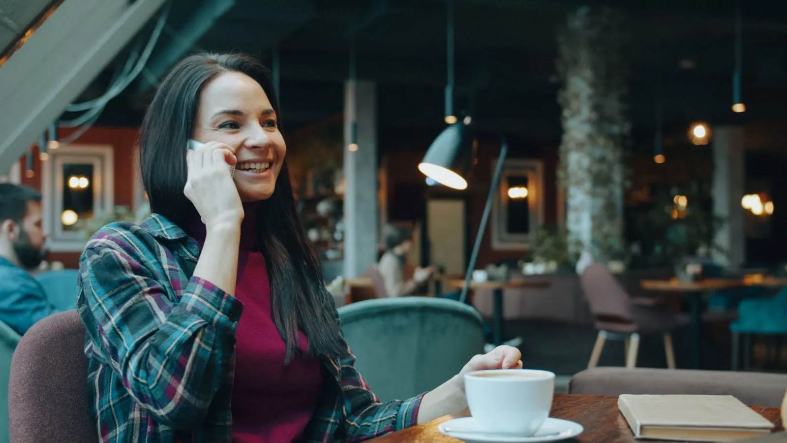 Kafede telefonla konuşan gülümseyen işletme sahibi