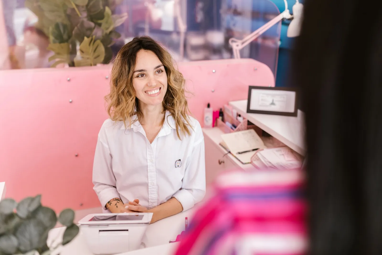 Salon resepsiyonunda gülümseyerek müşteri karşılayan çalışan